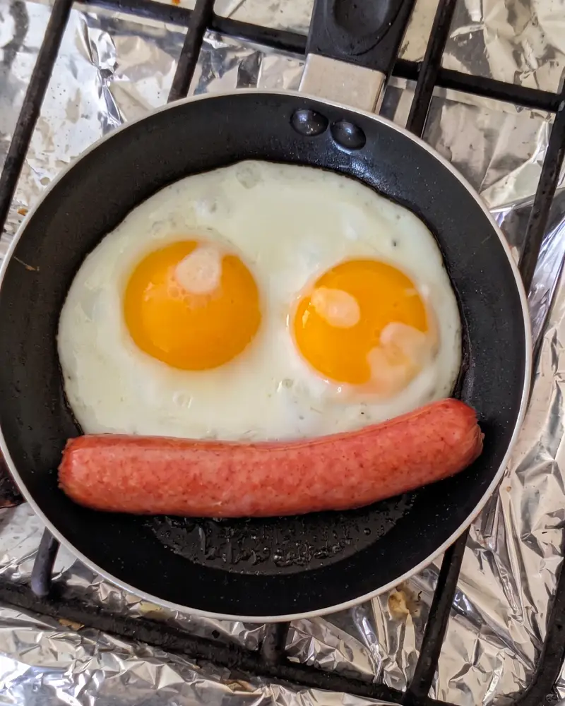 Fotografía de stock de dos huevos fritos con vienesa picada en un plato, almuerzo casero típico de la cocina chilena.